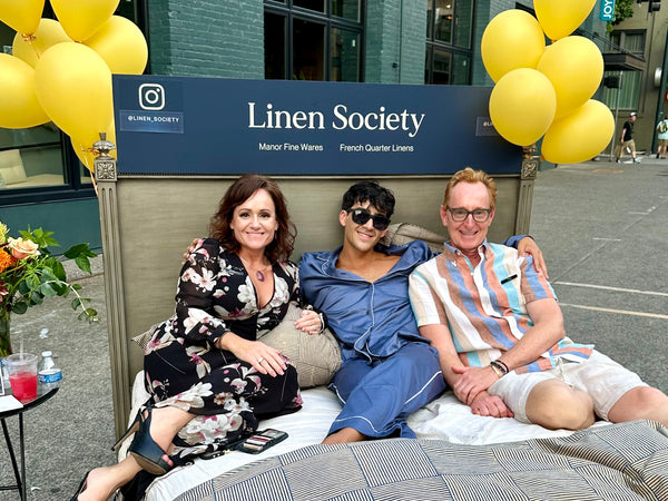 Image of three people sitting on a bed.