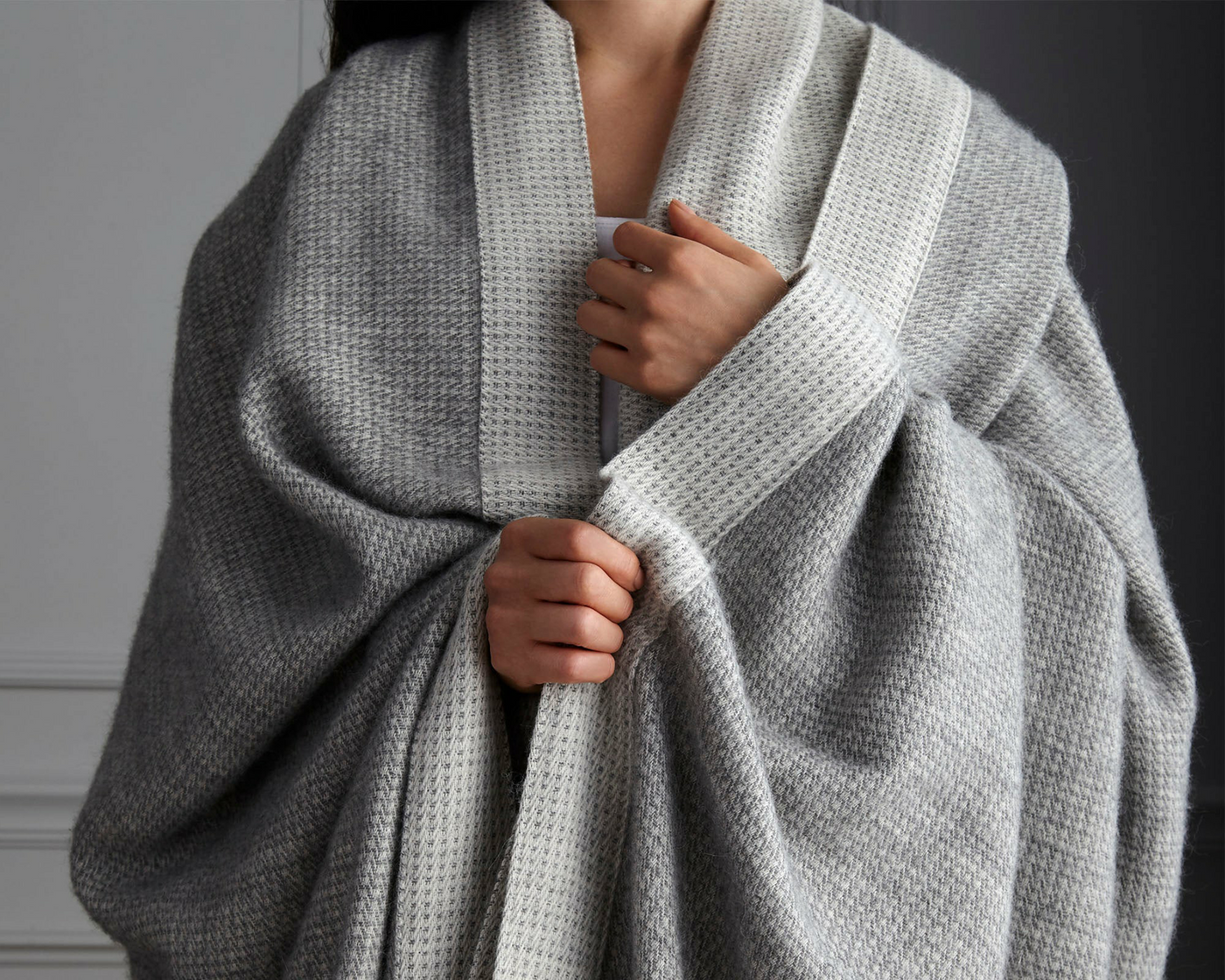 Woman wrapped in cozy gray cotton and alpaca Angelo blanket by Peacock Alley
