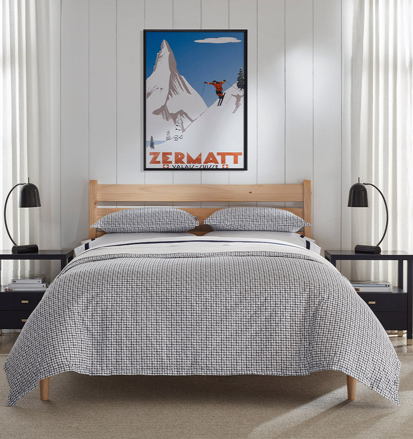 Caselle navy and white geometric patterned duvet cover and shams on a natural wood bed.