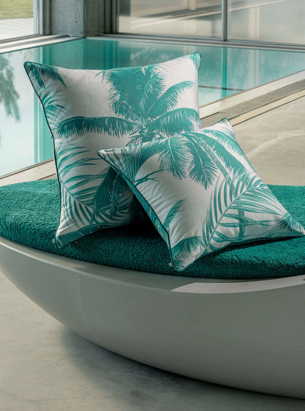 Cabo Verde cushions with teal palm print on white, styled on a teal cushioned outdoor daybed.