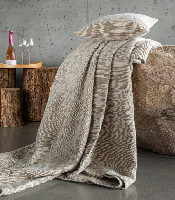 Panama textured linen throw and pillow in natural draped over a stone boulder.