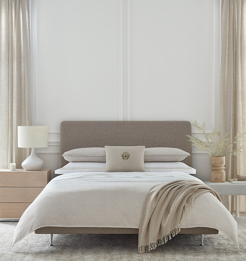 Dresano ivory bedding set styled on bed with taupe upholstered headboard.