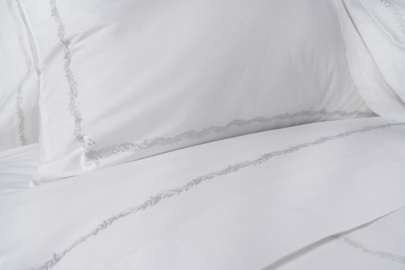 Sferra Foglia white cotton bedding with delicate grey embroidered leaf border detail.