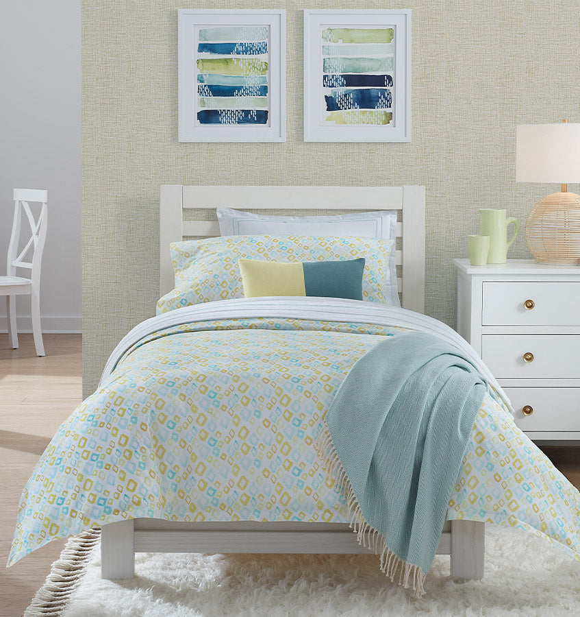 Geometrico bedding set in aqua and yellow geometric print on a white bed.