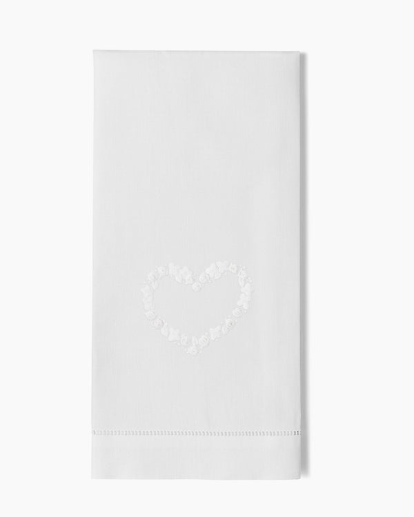 White linen guest towel with embroidered floral heart motif and hemstitch border.