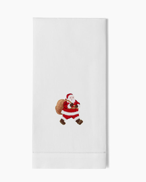 White linen hand towel with embroidered Santa Claus carrying a gift sack, hemstitch border.