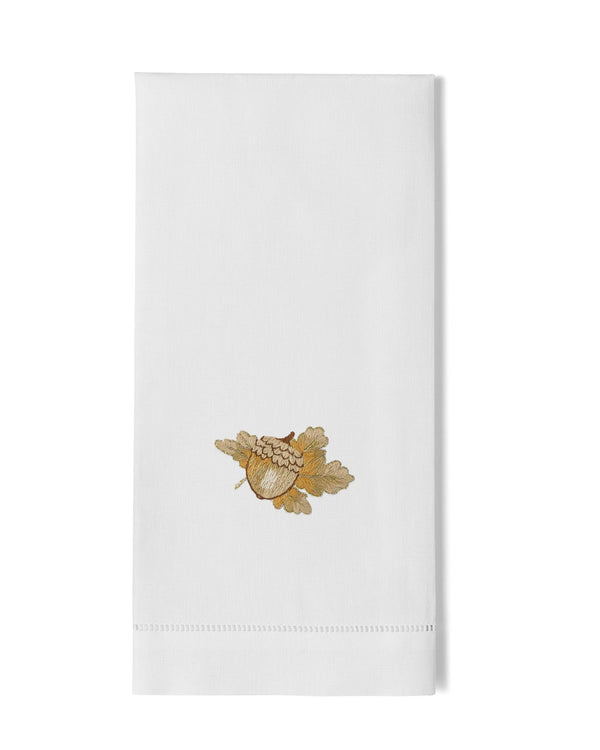 White linen hand towel with gold embroidered acorn and oak leaf motif, hemstitch border.