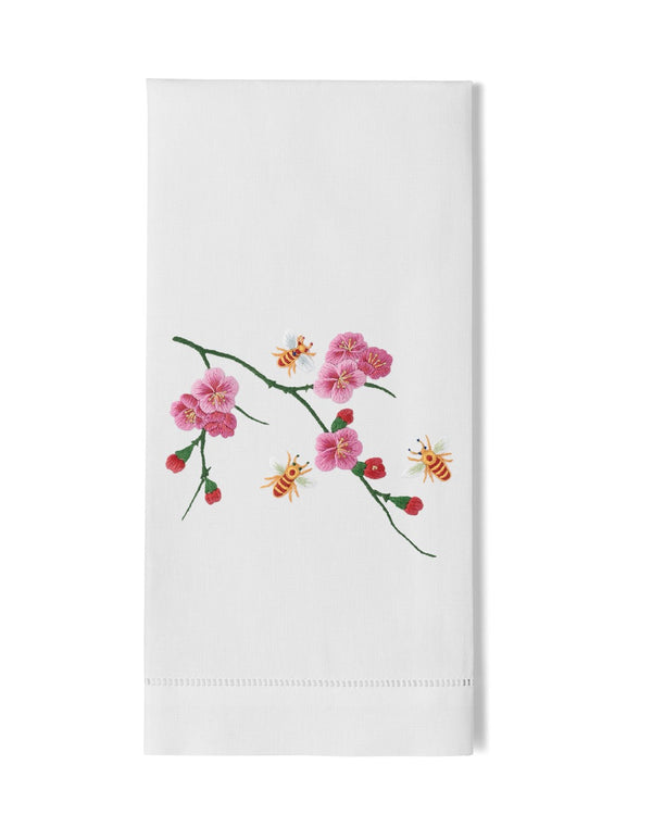 White linen hand towel with embroidered pink cherry blossoms and honeybees on a branch.