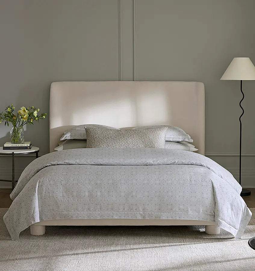 Maiolica bedding set in silver grey with geometric pattern on an upholstered bed.