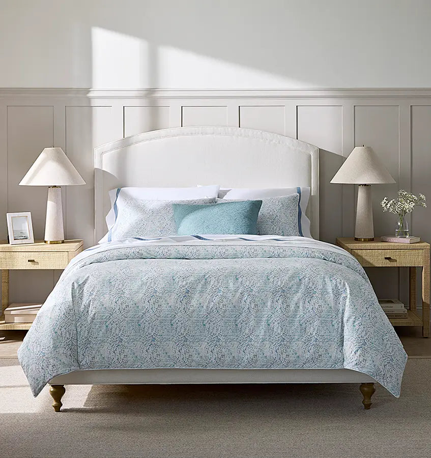 Meloria duvet cover in aqua paisley print styled on a bed with white headboard.