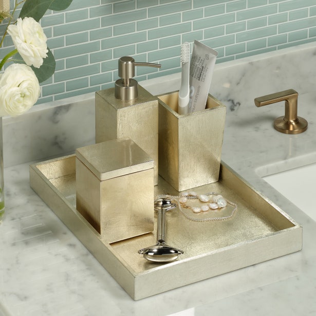 Davos champagne bath accessories set styled on marble countertop with green tile backdrop.