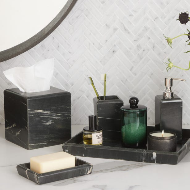 Black marble bath accessory set styled on white marble vanity with mirror.