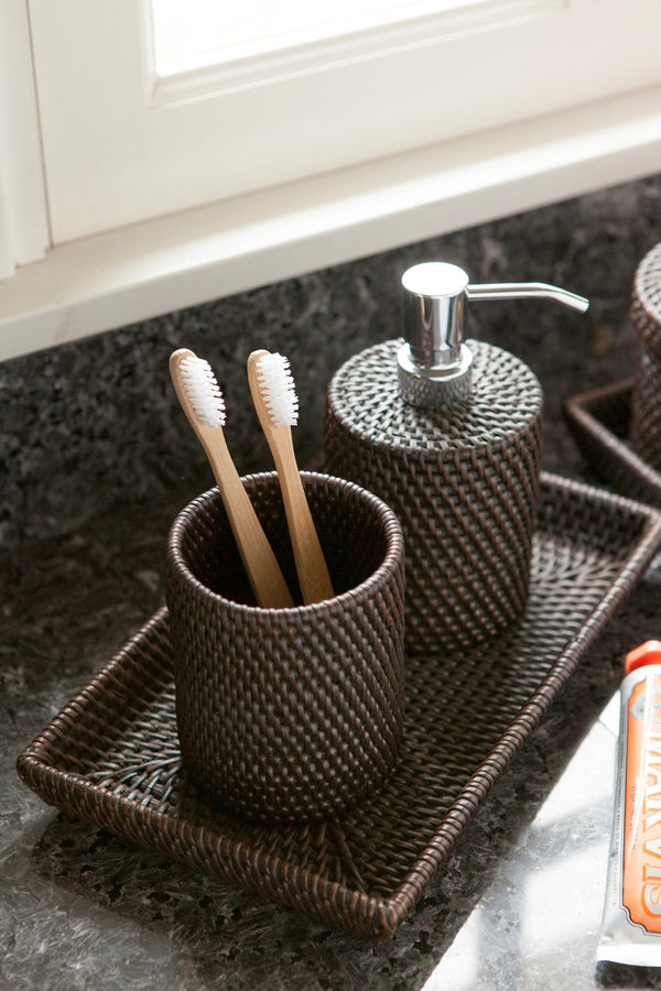 Dark rattan bathroom set with toothbrush holder, soap dispenser, and tray on granite counter.