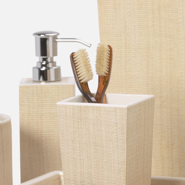 Close-up of Maranello bath accessories in ivory linen texture, toothbrush holder and soap dispenser.