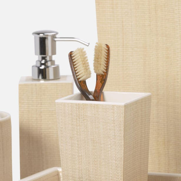 Close-up of Maranello bath accessories in ivory linen texture, toothbrush holder and soap dispenser.