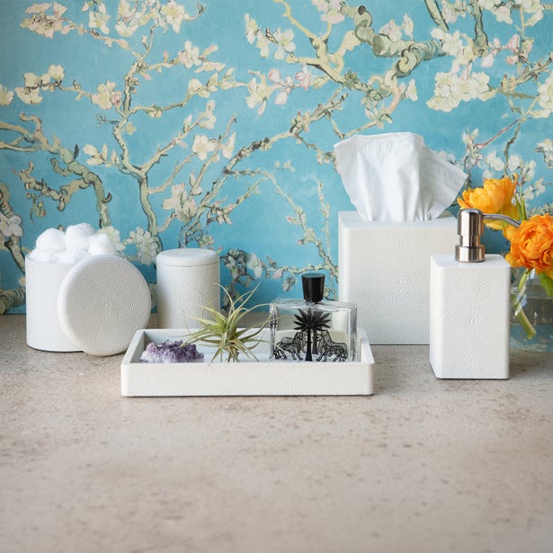 White textured bath accessories set with tray, tissue box, soap dispenser, and canister on stone surface.