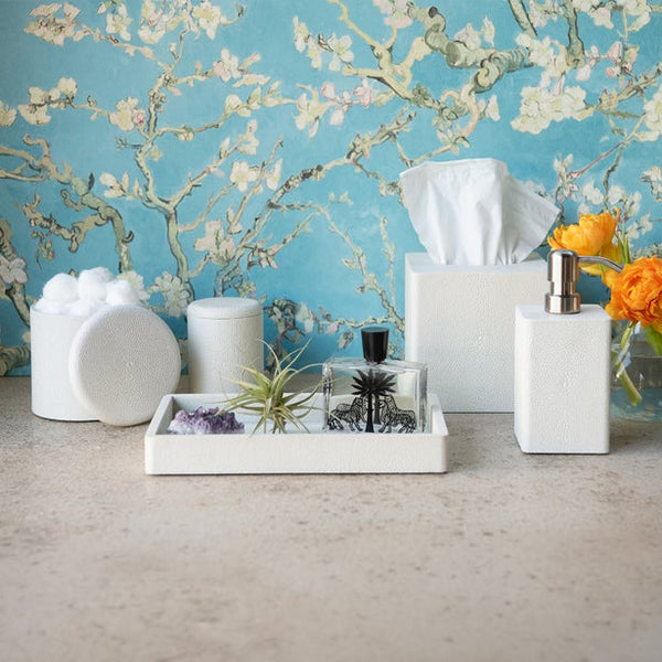 White textured bath accessories set with tray, tissue box, soap dispenser, and canister on stone surface.