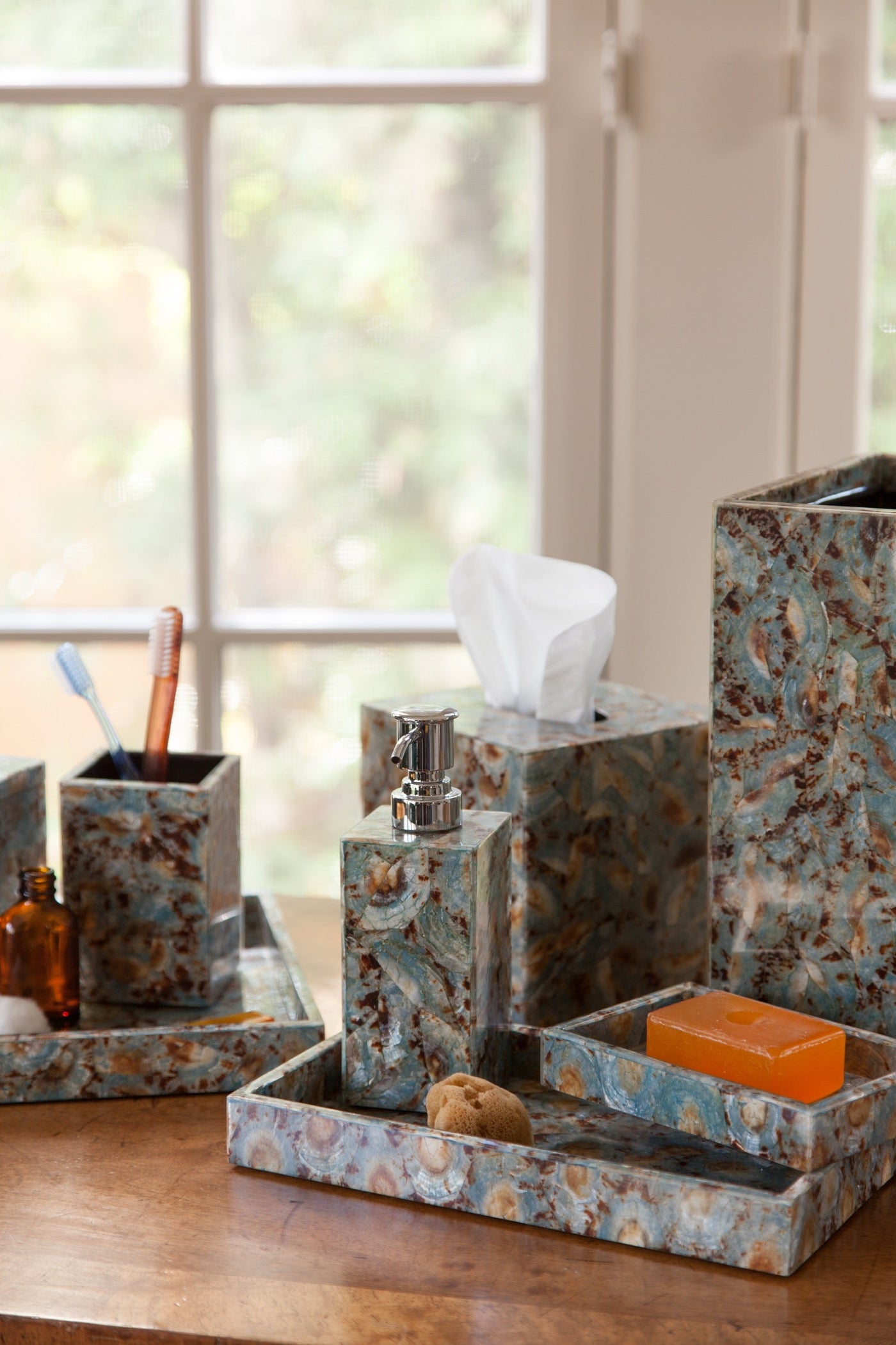 Sitges bath accessory set in marbled teal and brown, styled on a wooden vanity.