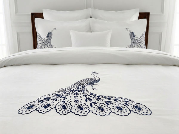 Peacock Collection white duvet cover with navy embroidered peacock, styled on a made bed.