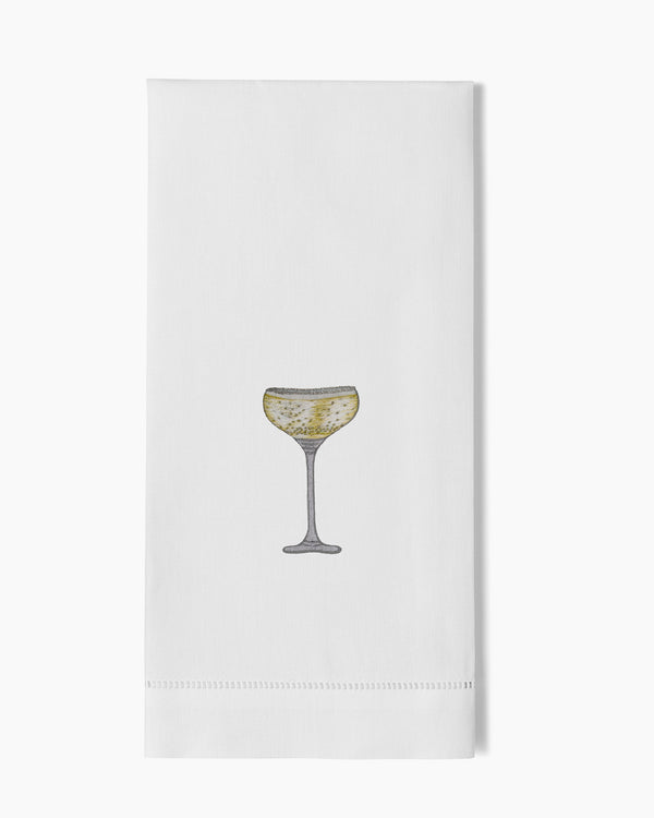 White linen hand towel with embroidered champagne coupe glass in gold and silver tones.