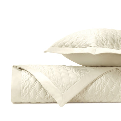 Abbey ivory quilted coverlet and sham set, folded, with floral diamond stitching.