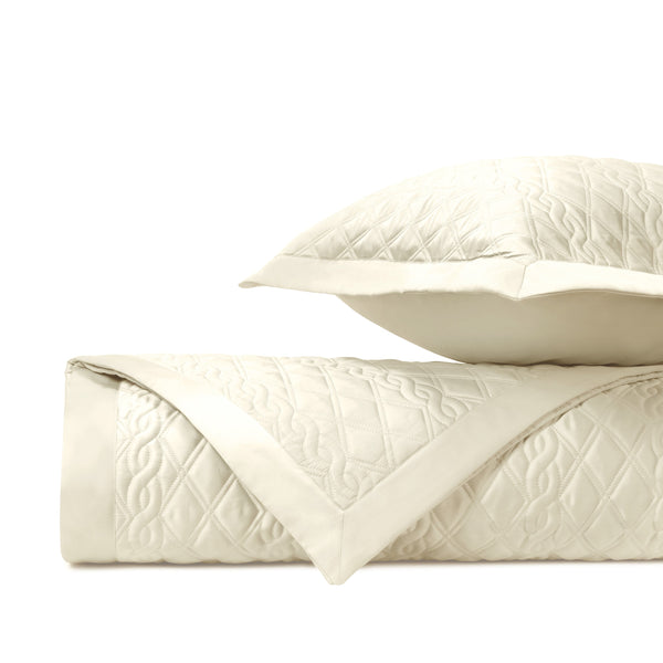 Abbey ivory quilted coverlet and sham set, folded, with floral diamond stitching.
