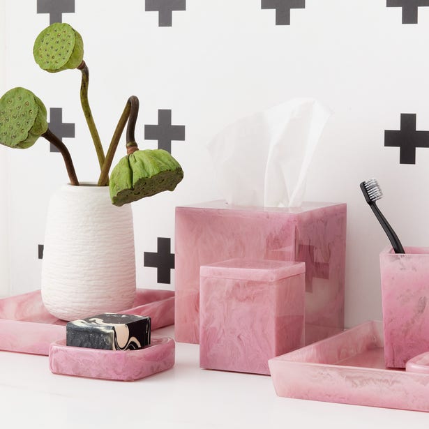 Abiko bath accessories set in blush resin, styled on a bathroom vanity with cross-pattern wall.