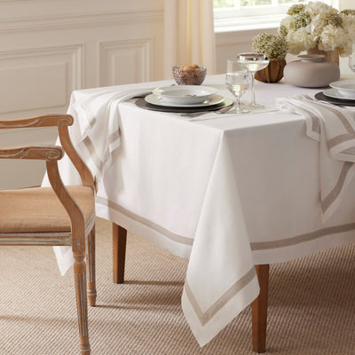 Alina white linen tablecloth with champagne border on a dressed dining table.