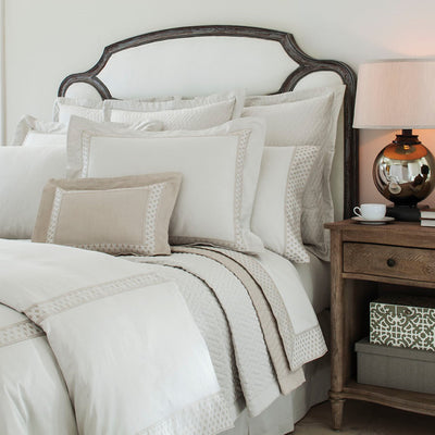 Ara ivory and taupe cotton bedding with geometric border on styled bed.