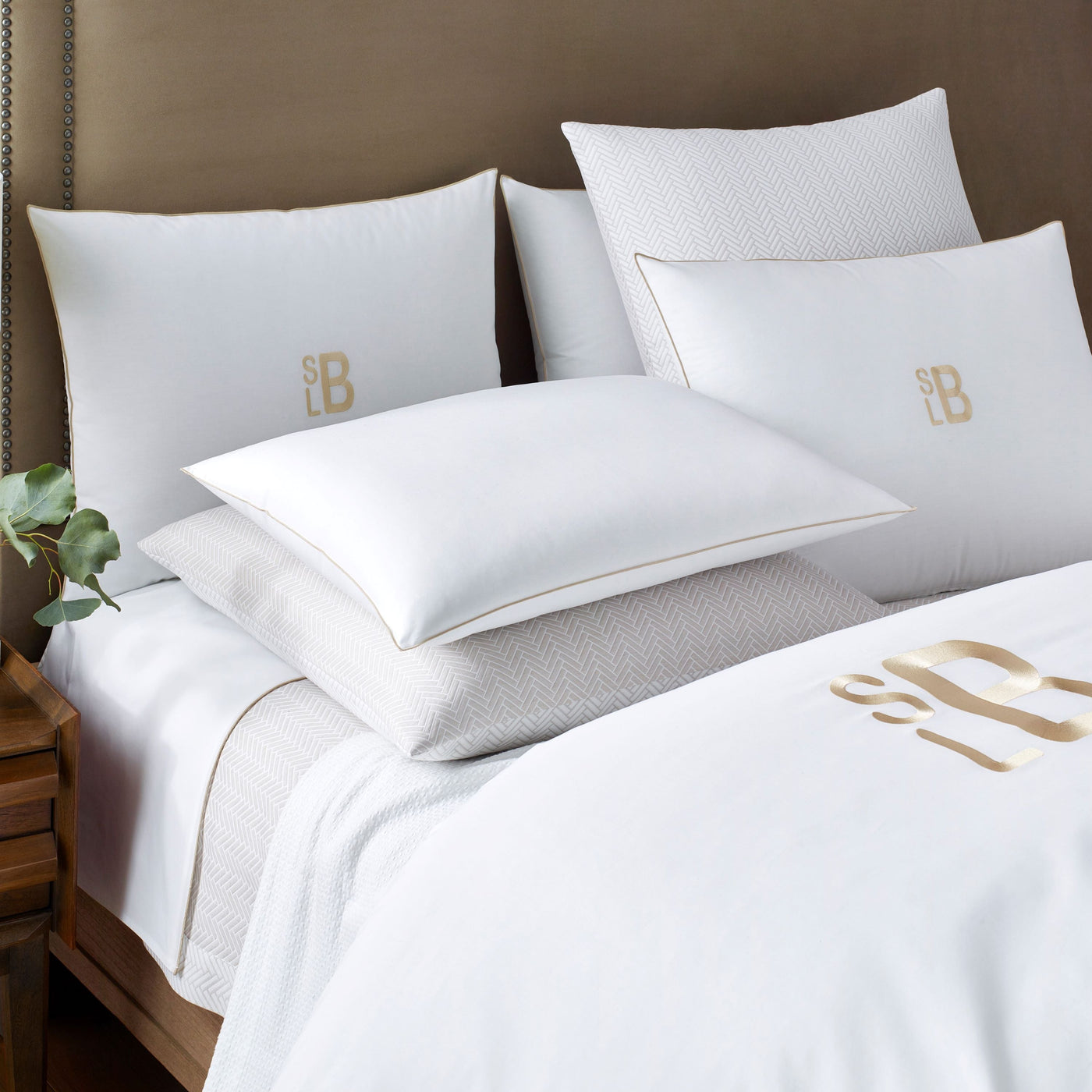 Thatcher white bedding set with gold monogram embroidery on bed with taupe accent.