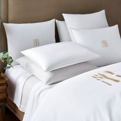 Sferra Arlo white bedding set with gold monogram embroidery on made bed.