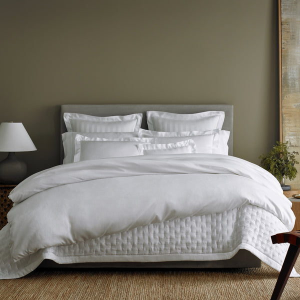 Home Treasures Athens white Egyptian cotton bedding with satin border on styled bed.