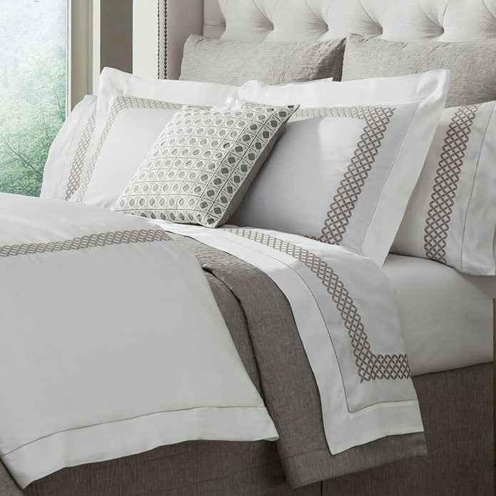 Sferra Avalon white bedding with taupe geometric embroidered border on bed.