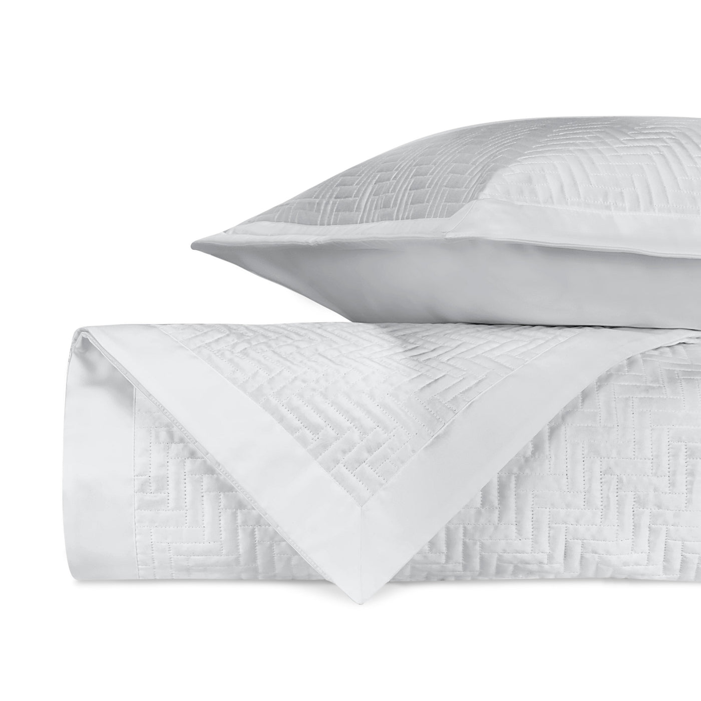 Baxter white quilted coverlet and sham with herringbone texture, folded and stacked.