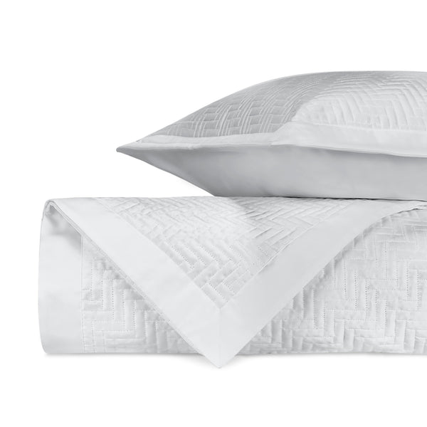Baxter white quilted coverlet and sham with herringbone texture, folded and stacked.