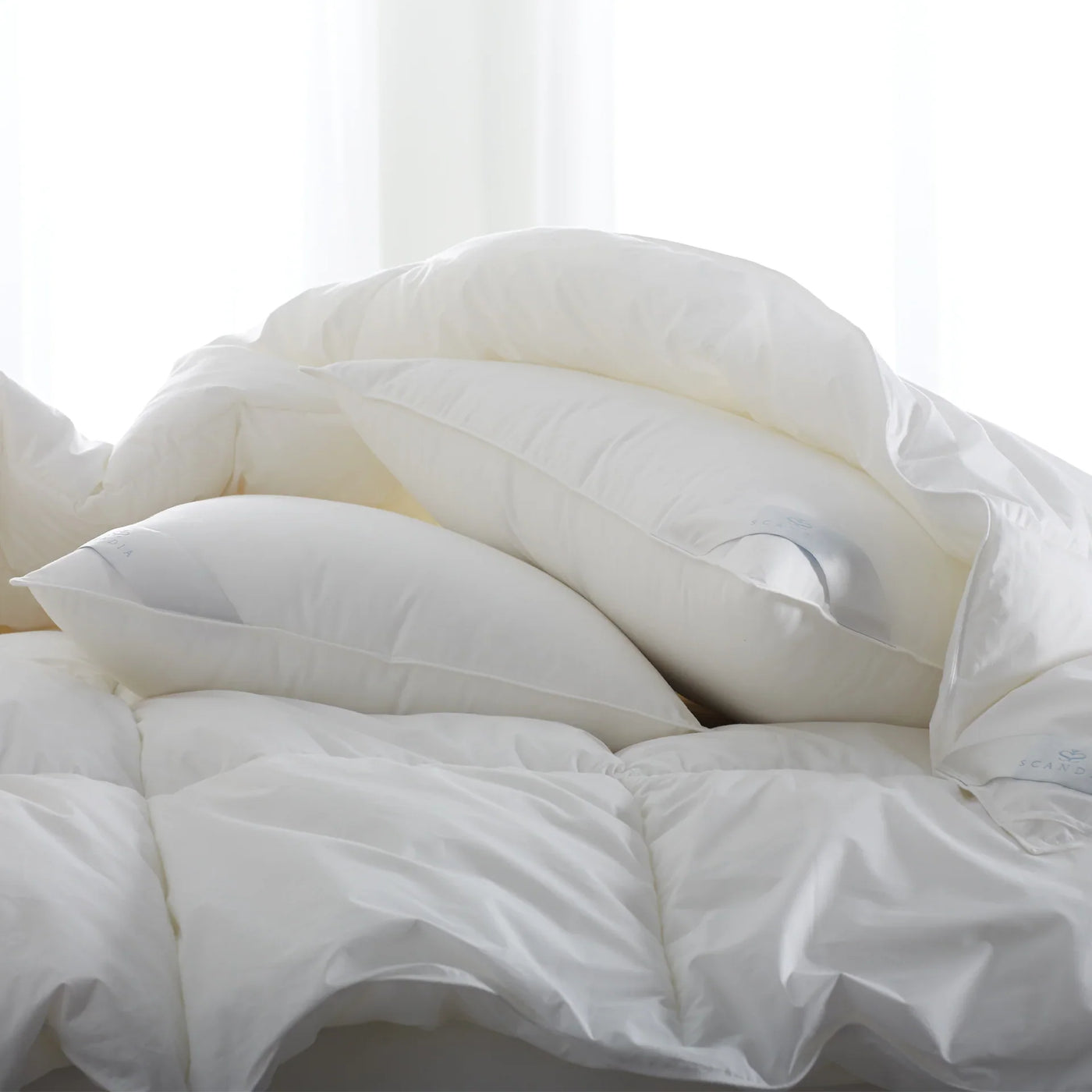 Bergen Down-Free duvet and pillow inserts in ivory, shown fluffy and layered.