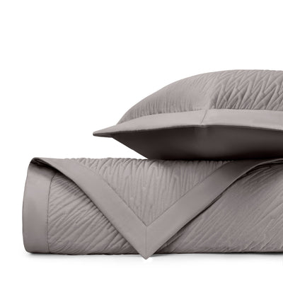 Blaze quilted coverlet and sham in taupe with wave-textured pattern, folded and stacked.