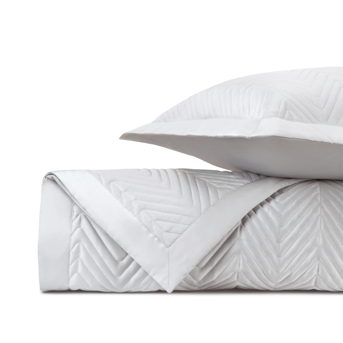 Charleston quilted white coverlet and pillow sham with chevron stitching, neatly folded.
