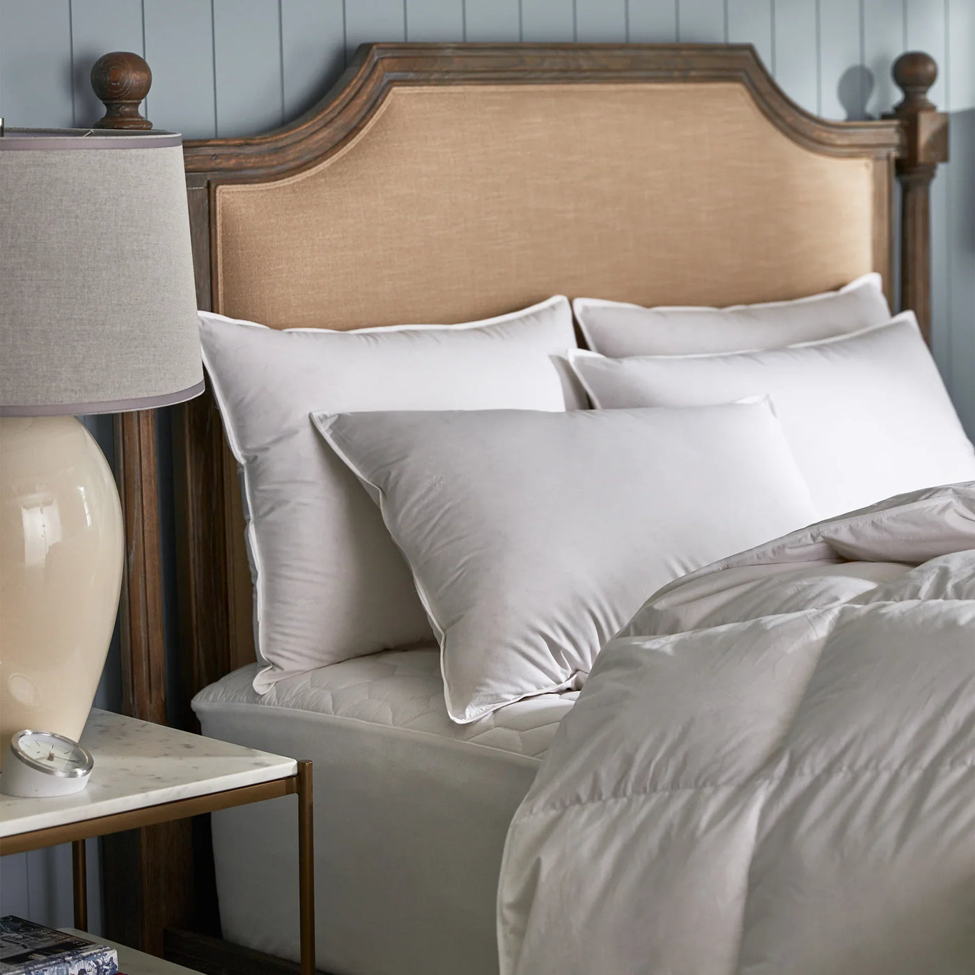 Copenhagen Down Collection pillows in white, styled on a bed with grey bedding.