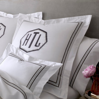 White cotton euro sham with charcoal double-stripe border and monogram embroidery.