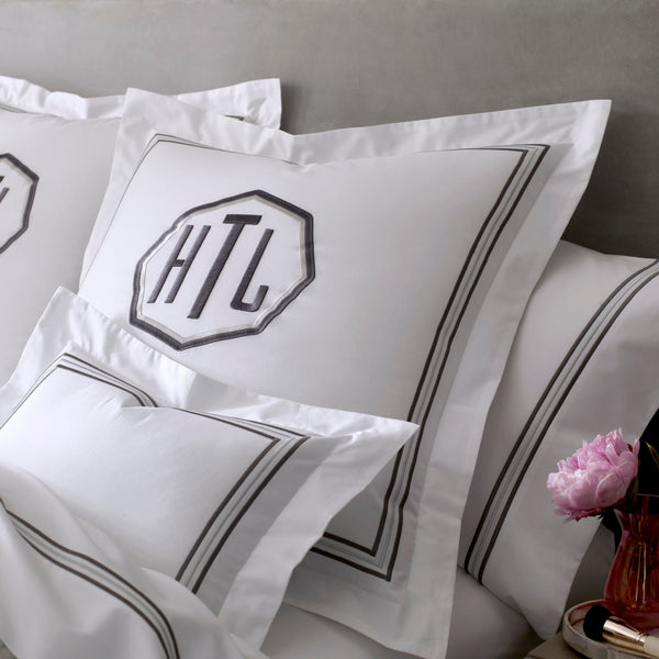 White cotton euro sham with charcoal double-stripe border and monogram embroidery.