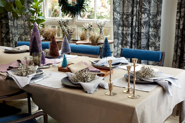Chamant linen tablecloth and napkins in sand styled with brass candlesticks and holiday decor.