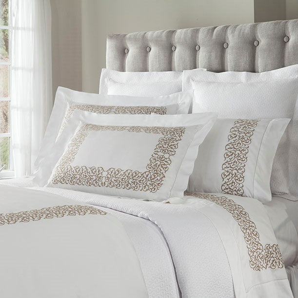 Sferra Jasmine white bedding with champagne embroidered scroll border on bed.