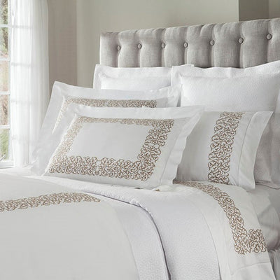 Sferra Jasmine white bedding with champagne embroidered scroll border on bed.