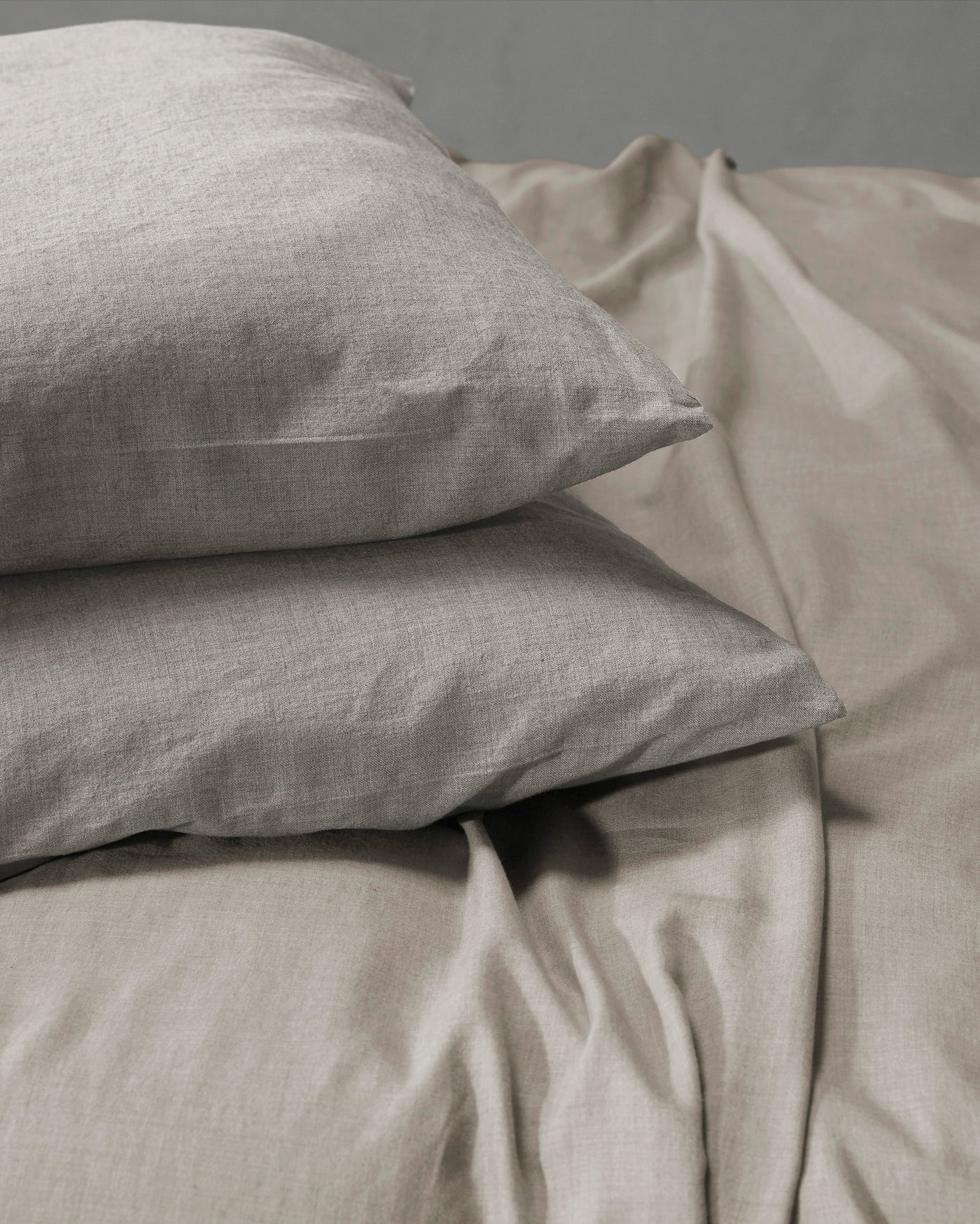Smir cashmere bedding set with two stacked pillowcases in warm grey linen.