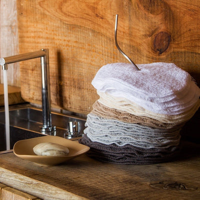 Abyss towels stacked in ombre shades from white to charcoal on a wood counter.