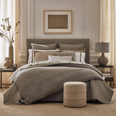 Loren taupe textured bedding collection on styled bed with layered pillows.