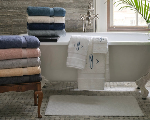 Matouk Lotus Towels in a variety of colors in a bright bathroom with a clawfoot tub. Featuring a monogram on the white towels.
