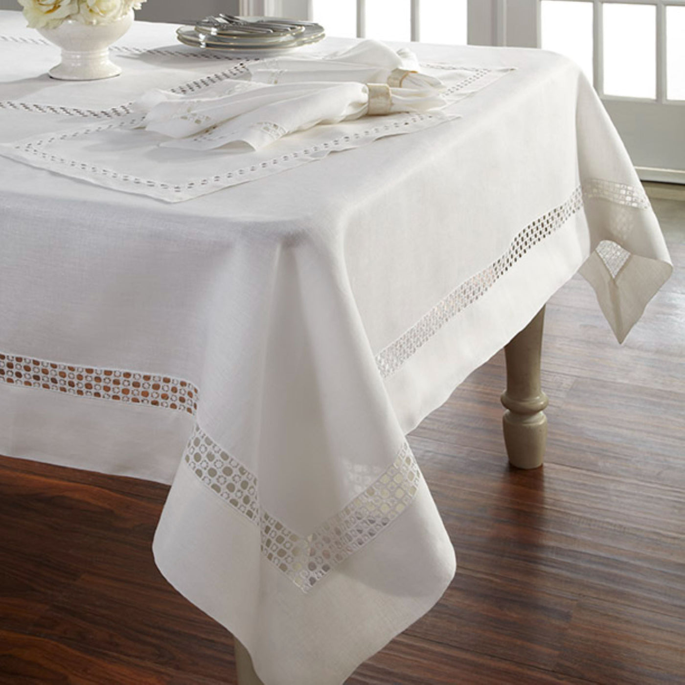 Sferra Lotus ivory linen tablecloth with geometric drawn-thread border on dining table.