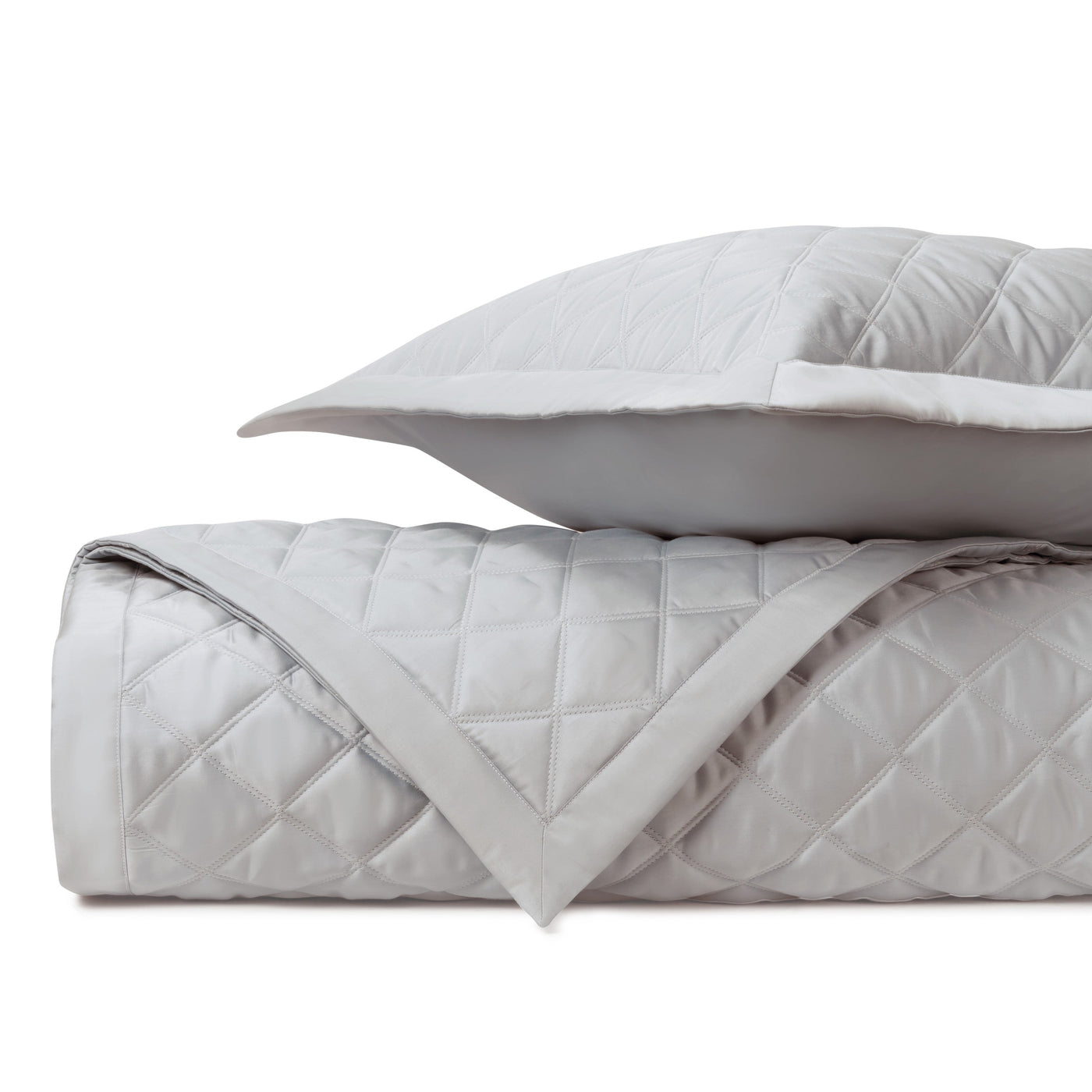 Mesa quilted coverlet and sham in silver-grey with diamond stitching, folded on white background.